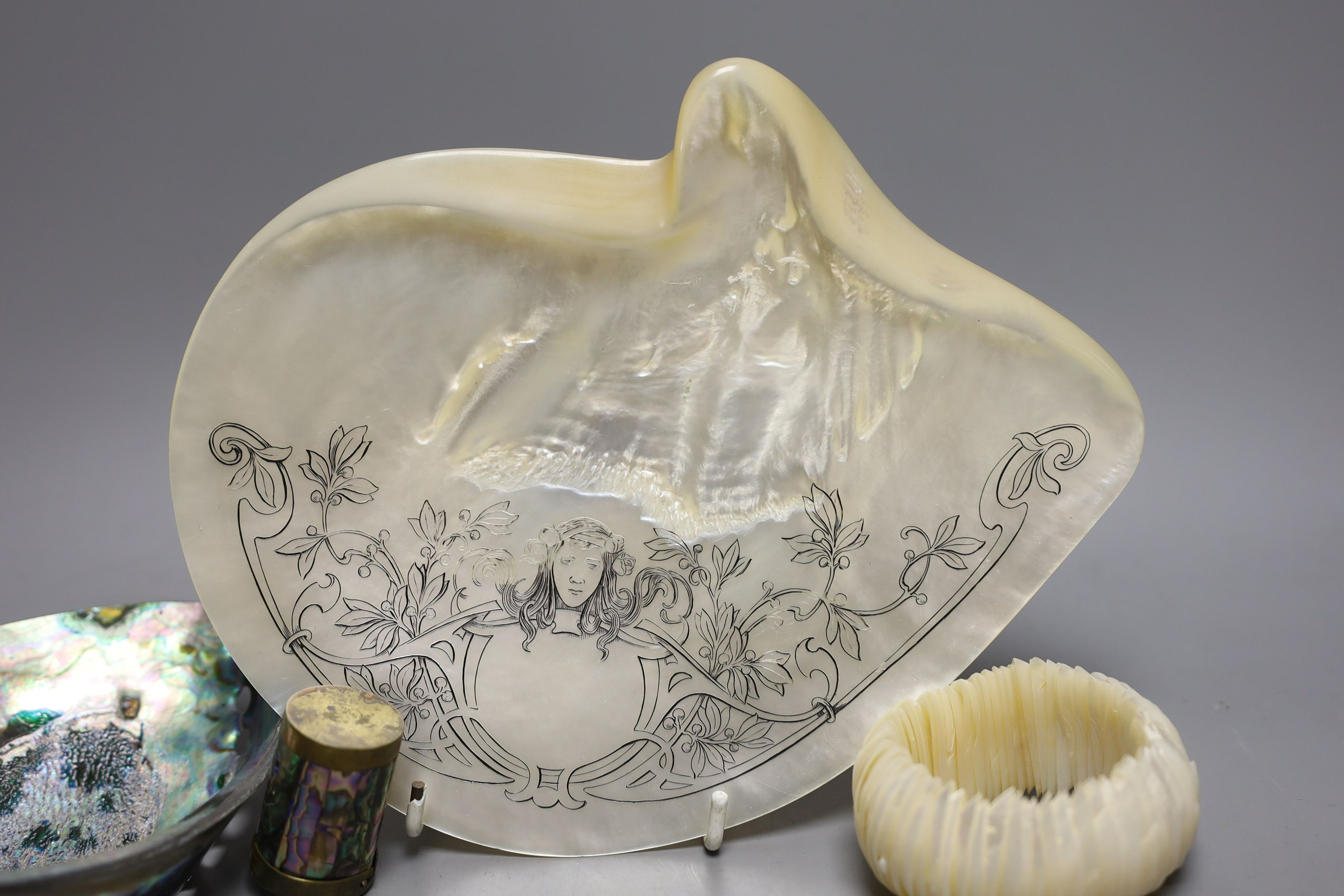 An engraved pearl shell, 22cm, a cylindrical box and bracelet, and two abalone shells